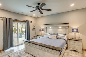 A bedroom with a bed, two bedside tables, a ceiling fan, and a sliding glass door leading to an outdoor area. - Spacious Patio & Yard! Family Home in Byrdstown (Byrdstown)