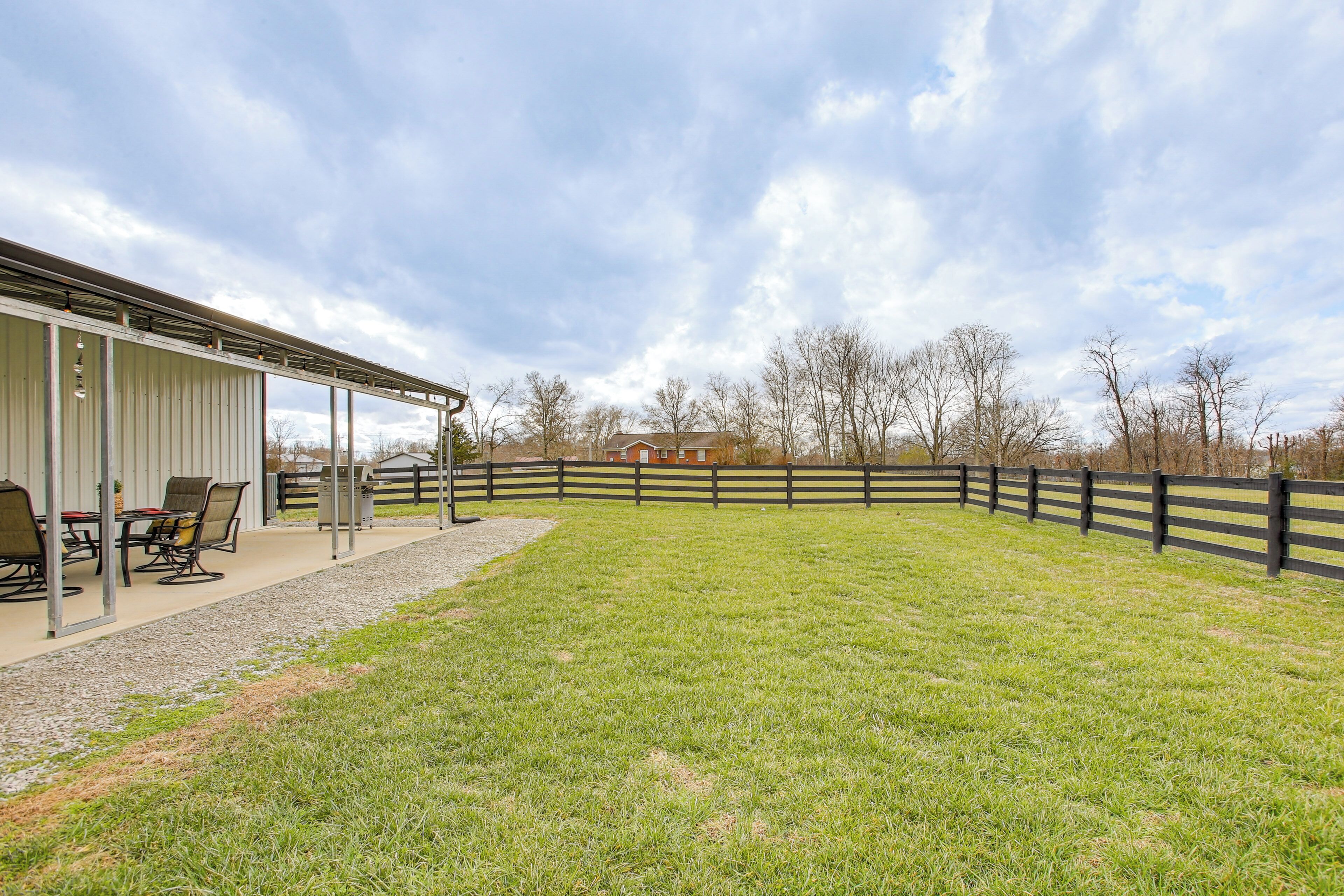 A covered patio area with outdoor seating and a view of a fenced property.