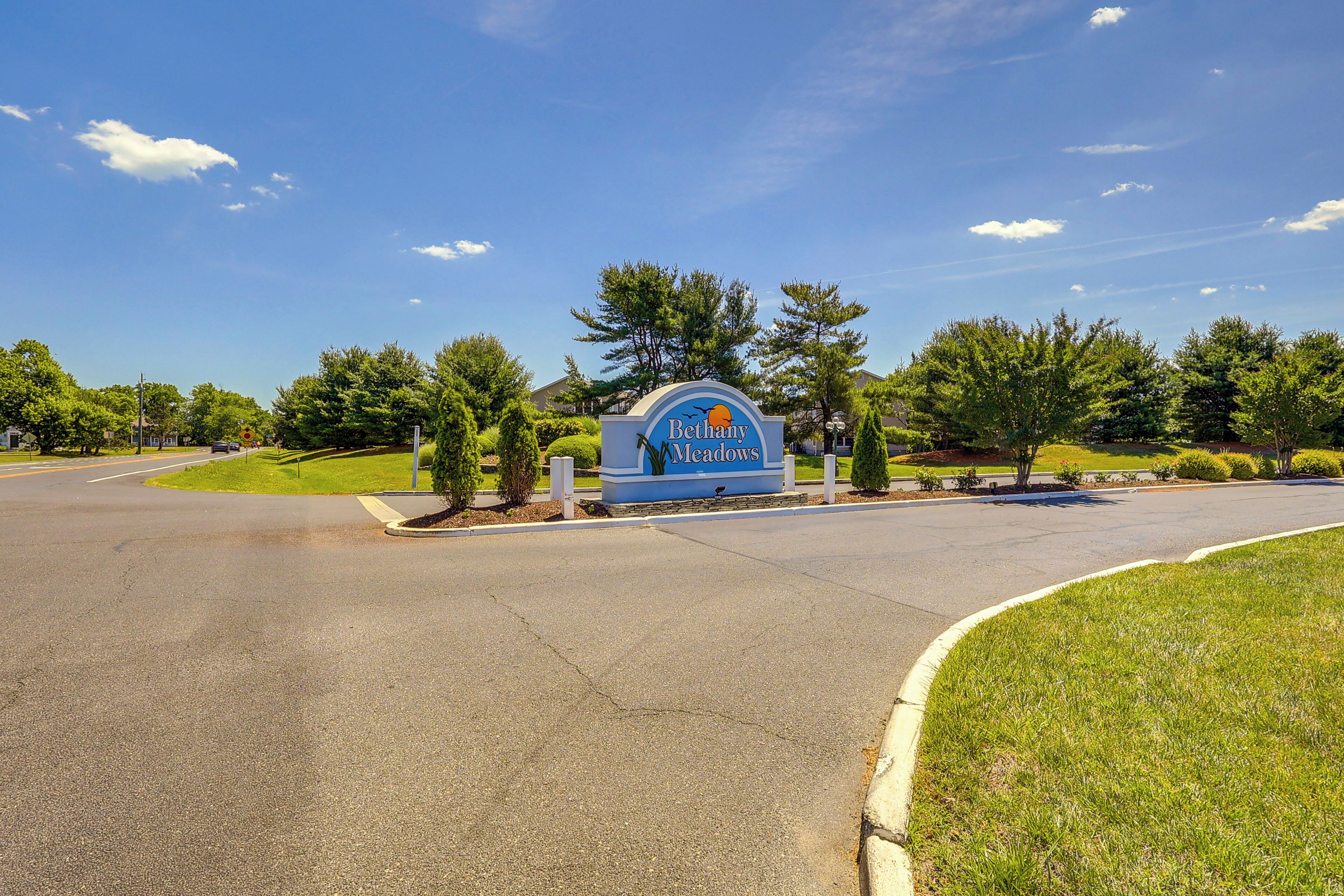 A sign for "Bethany Meadows" with a curved road leading to it, surrounded by greenery and trees.
