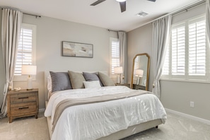 A bedroom with a bed, nightstands, a mirror, and a ceiling fan. - Serene Outdoor Space: Group Getaway in Maricopa! (Maricopa)