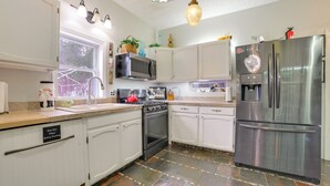 Une cuisine moderne avec des meubles blancs, des appareils en acier inoxydable et un sol carrelé.