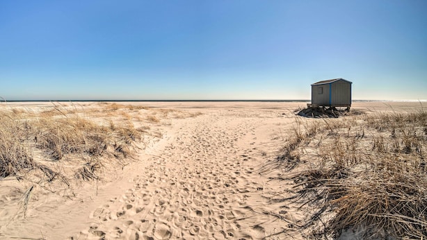 A sandy beach with a small, single-story building. - Steps to Brigantine Beach: New Jersey Beach Condo (Brigantine)