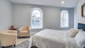 Ein modernes Schlafzimmer mit einem großen Bett, zwei Sesseln und einem kleinen Tisch.