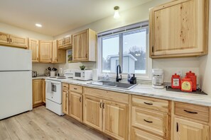 A modern kitchen with wooden cabinets, a white refrigerator, a microwave, and a coffee maker.