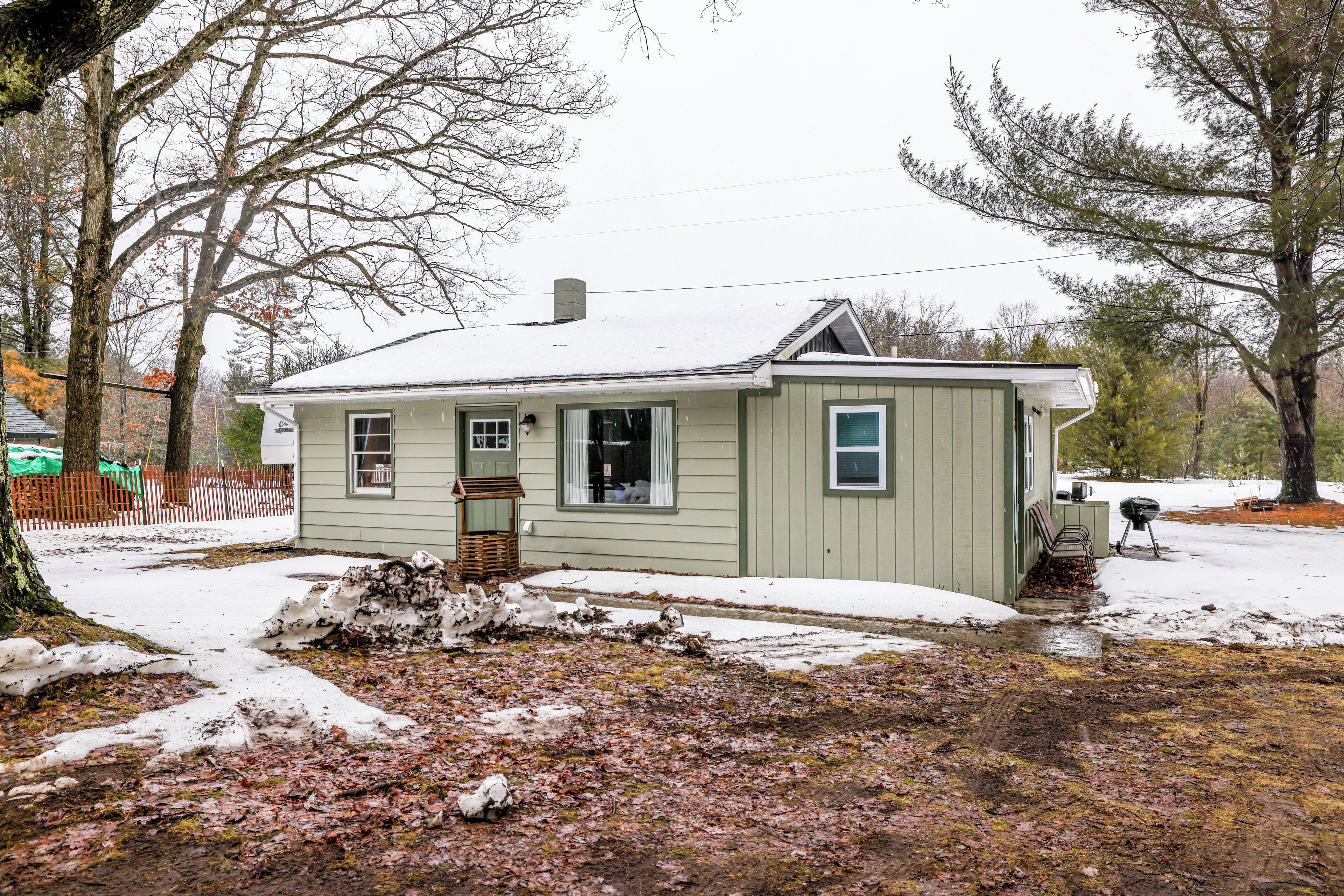 A small, single-story house with a snow-covered roof and a front porch.