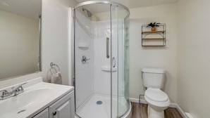 Un bagno moderno con doccia vetrata, un water bianco e un lavabo con specchio.