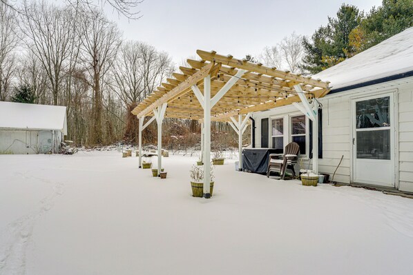 Un patio couvert agrémenté d’une pergola en bois, de plantes en pot et d’un espace salon.