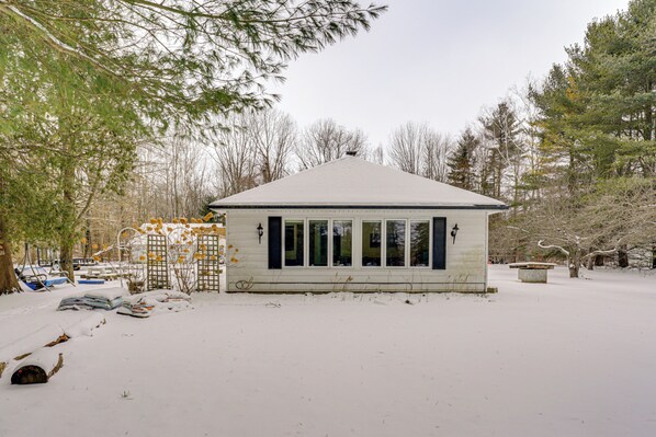 A small, single-story building with a sloped roof, surrounded by snow-covered ground and trees. - Woodsy & Charming! Applegate Cabin w/ Large Yard (Applegate)