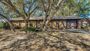 A two-story house with a brick exterior, a garage, and a large tree in front. - Beach Gear & Cruiser Bicycles: Quiet Pensacola Gem (Pensacola)