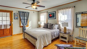 A bedroom with a bed, bedside tables, a chair, a ceiling fan, and curtains. - Bring Your Boat! Woodsy Cottage Near Fayetteville (Fayetteville)