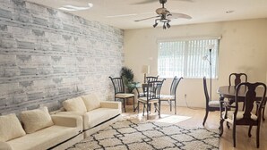 A living room with a sofa, chairs, a dining table, and a patterned rug. - SamAria - Two-story Villa (Deltona)