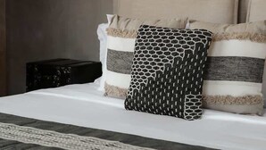 Un lit avec une tête de lit, des oreillers et un luminaire suspendu.