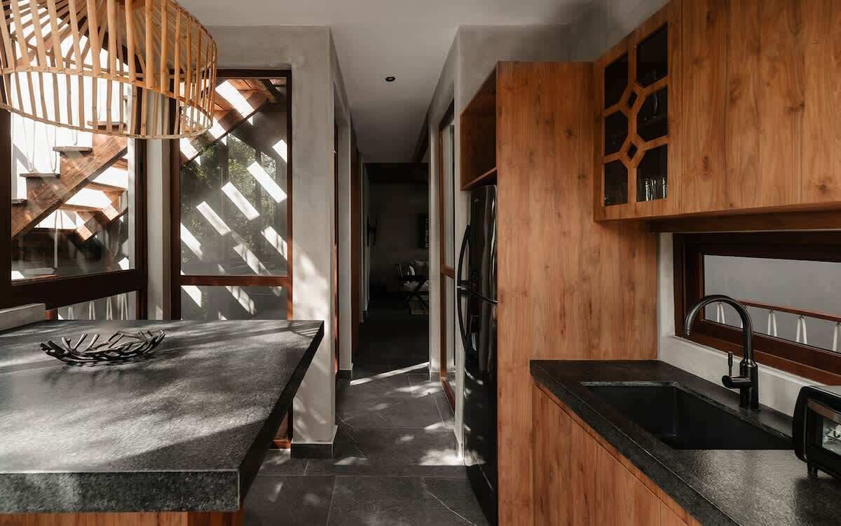 Een moderne keuken met een houten accentmuur, een zwart aanrecht en een inbouwkoelkast.