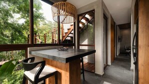 Une cuisine moderne dotée d’une grande fenêtre, d’un îlot central en bois et d’un escalier menant à un niveau supérieur.