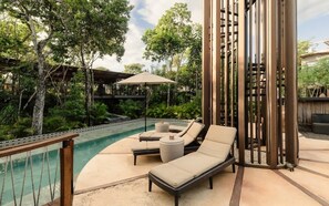 A poolside area with lounge chairs, a small table, and a pergola structure. - Siwa Jungle Romance C1-002 Beach Club Access (Tulum)
