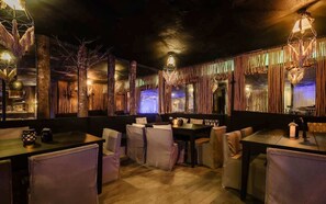 A restaurant with wooden tables and chairs, hanging lights, and a rustic ambiance. - Siwa Jungle Romance C1-002 Beach Club Access (Tulum)
