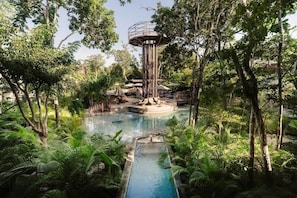 A pool surrounded by lush greenery, a central tower, and a covered seating area. - Siwa Jungle Romance C1-002 Beach Club Access (Tulum)