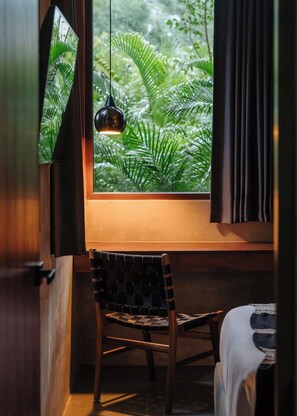 A room with a window, a hanging light, a chair, and a bed. - Siwa Jungle Romance C1-002 Beach Club Access (Tulum)