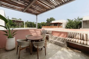 An outdoor patio with a round table and chairs, a cushioned bench, and a potted plant. - Casa De Oro Jungle Villa Minutes from beach (Tulum)