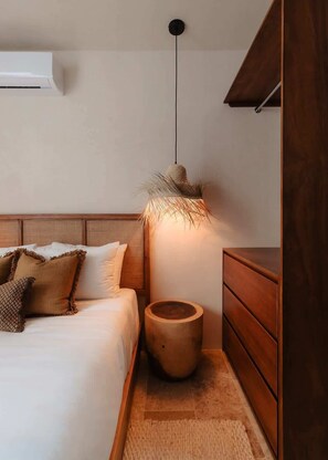 Ein Schlafzimmer mit Bett, Nachttisch, Holzkommode und einer Pendelleuchte.