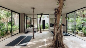 Ein modernes Interieur mit großen Glasüren, einem zentralen Baum, schwarzen Matten und einem Boxsack.