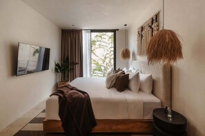 Ein modernes Schlafzimmer mit einem großen Bett, einem Fernseher, einer Topfpflanze und einem Ausblick durch ein Fenster.