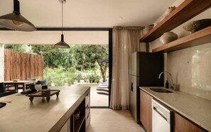 A modern kitchen with a large window, wooden cabinets, and a built-in dishwasher. - Nahara Jungle Chic Retreat Near the Beach (Tulum)