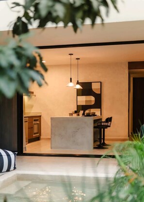 A modern kitchen with pendant lighting, a central island, and a dining area with chairs. - Nahara Jungle Chic Retreat Near the Beach (Tulum)