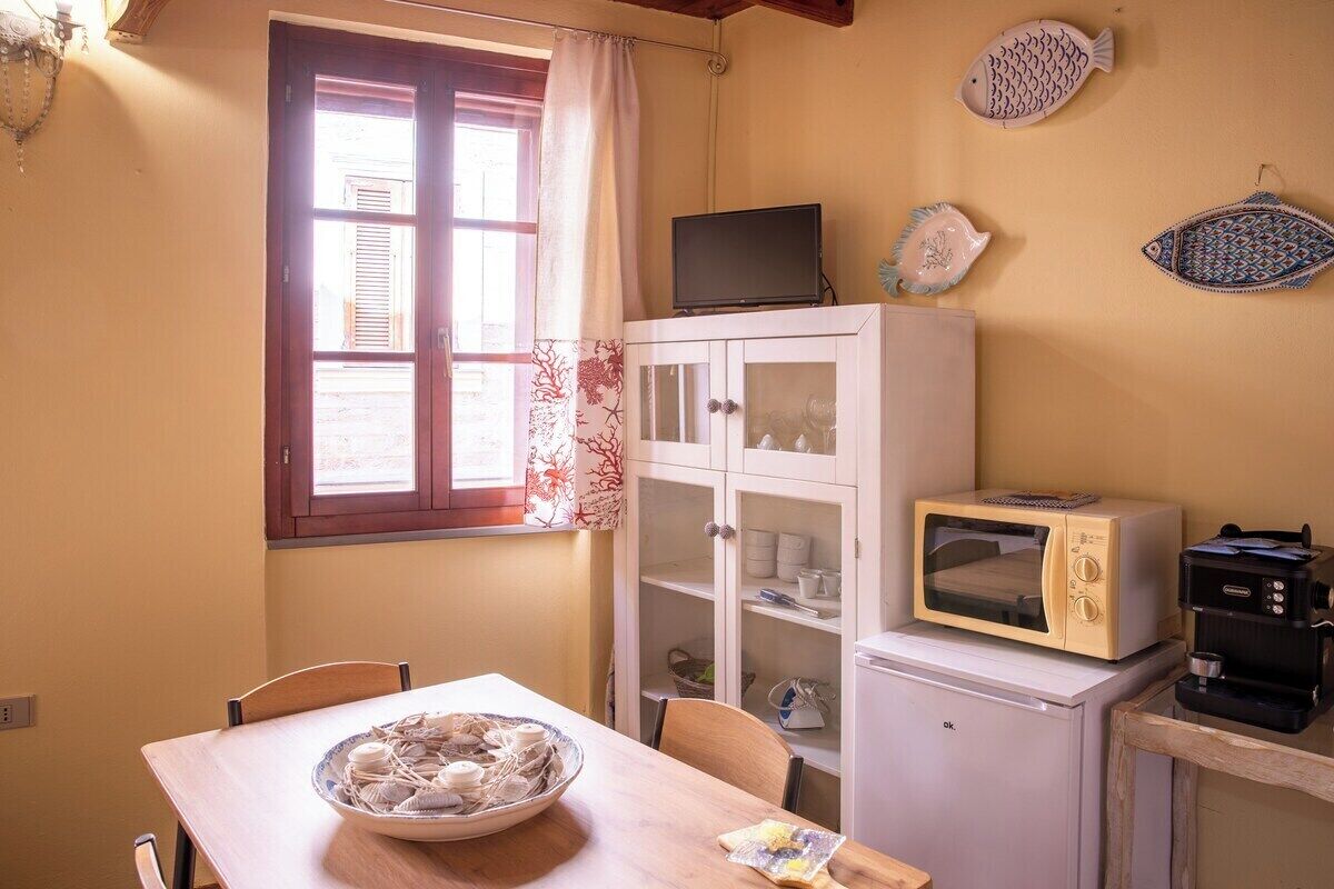 Eine kompakte Küche mit Esstisch, einer Mikrowelle, einer Kaffeemaschine und einem Schrank mit Glastüren.