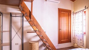Ein Schlafzimmer mit einer Holztreppe, einem Bett mit Handtüchern, einem Kleiderschrank und einem Fenster mit Vorhängen.