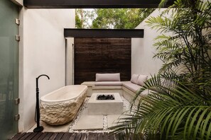 A modern outdoor bathroom with a stone bathtub, a fire pit, and a seating area with cushions. - Villa Anunna Luxe Tulum Villa Beach Club Access (Tulum)