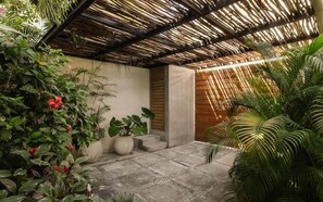 A covered outdoor area with a thatched roof, potted plants, and a concrete floor. - Villa Anunna Luxe Tulum Villa Beach Club Access (Tulum)