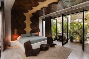A modern bedroom with a bed, a seating area, and a view of the outdoors. - Villa Anunna Luxe Tulum Villa Beach Club Access (Tulum)