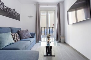 A modern living room with a grey sofa, a glass coffee table, and a view of the street through a large window. - DownTown La Latina Grupos, by MoNARO (Madrid)