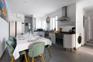 Una cocina moderna con comedor, que cuenta con una isla grande, electrodomésticos integrados y vistas al comedor contiguo.