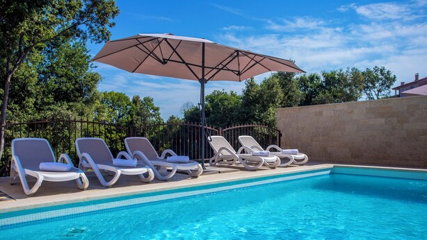 Una piscina amb gandules i un parasol gran.