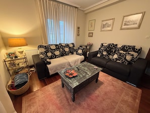 A living room with a sofa, a coffee table, a lamp, and framed pictures on the wall.