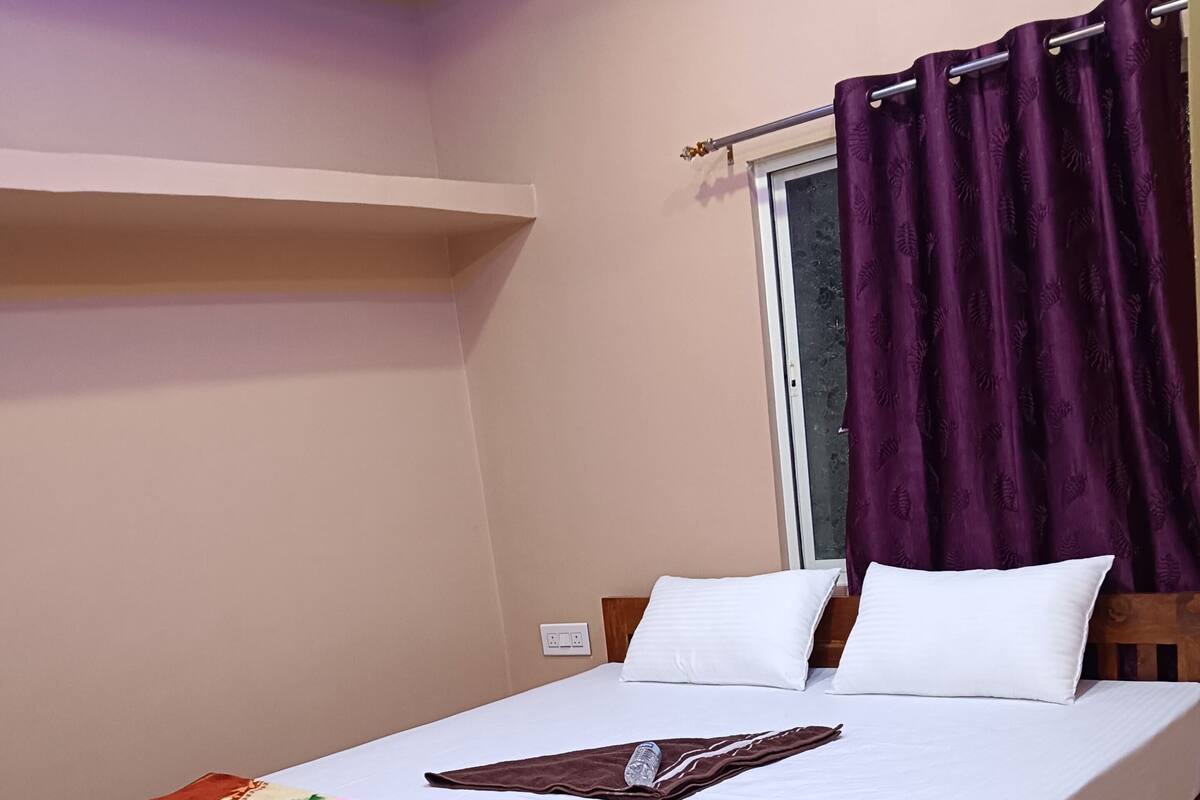 A single bed with a floral bedspread, white pillows, and a wooden headboard.
