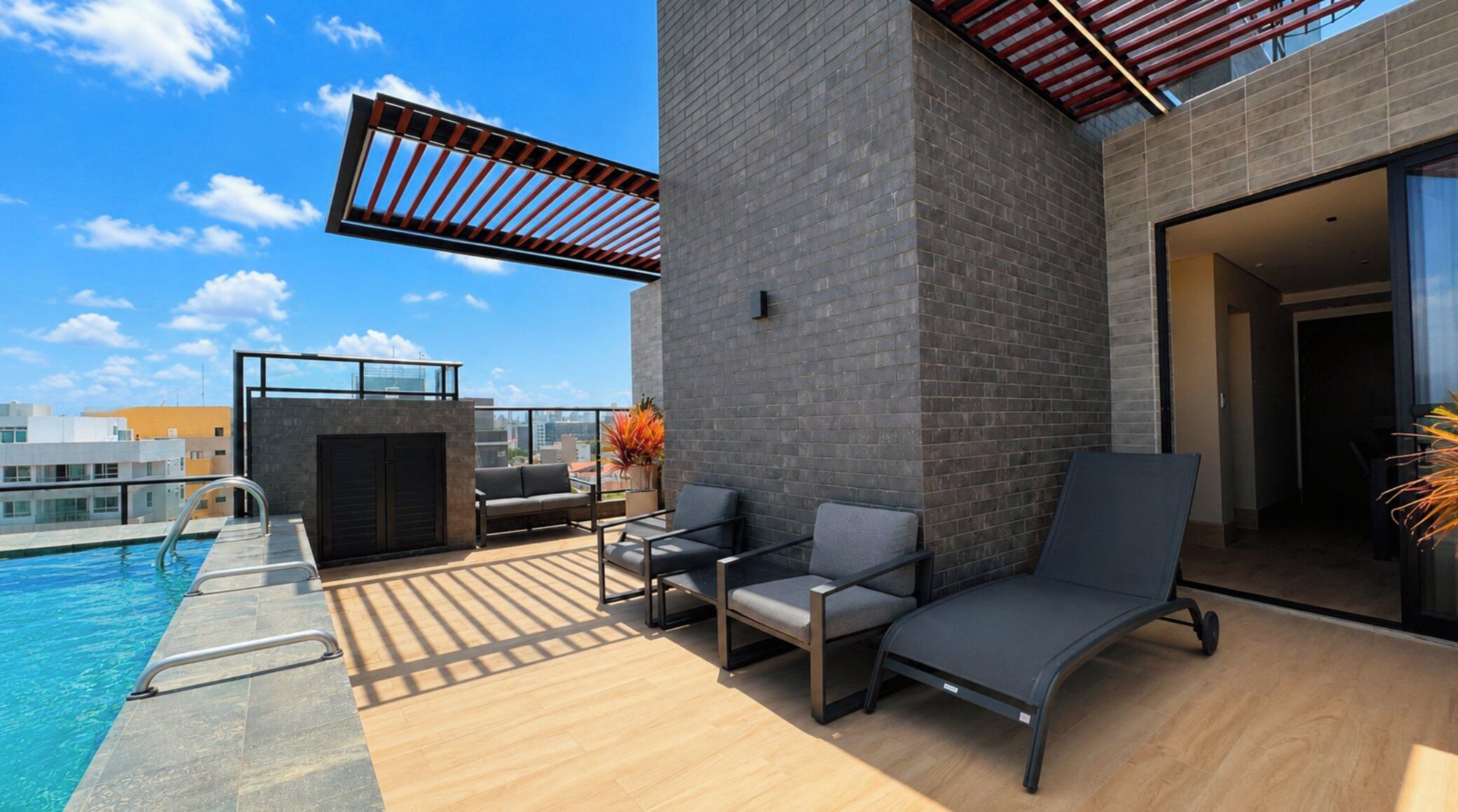 Terraço no telhado com piscina, área de estar e vista para o horizonte da cidade.