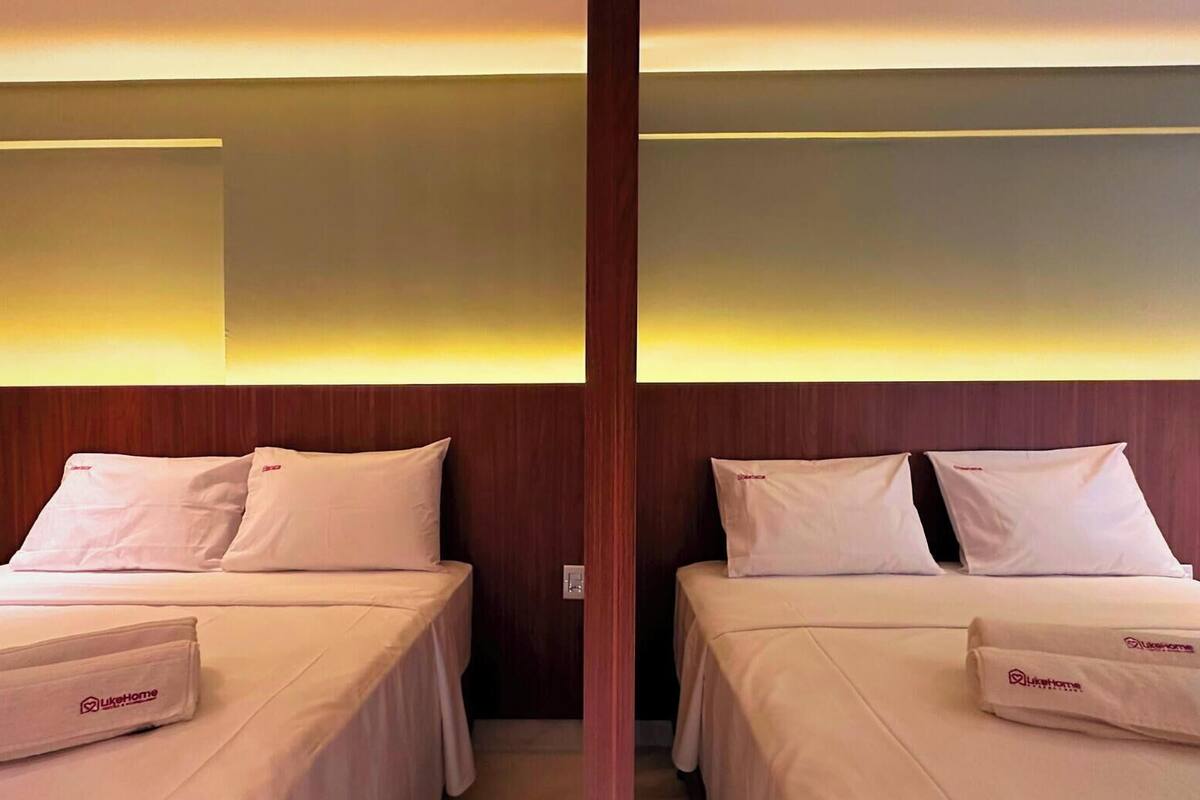 A hotel room with two beds, each with a pillow and a towel with the hotel logo.