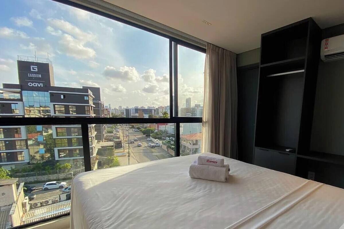 A hotel room with a large bed, a TV, and a view of a cityscape.
