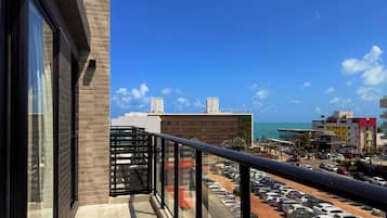 Uma varanda com vista para um estacionamento e edifícios, incluindo um hotel com telhado vermelho.