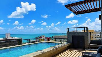 Piscina no terraço com vista para o oceano e o horizonte da cidade.