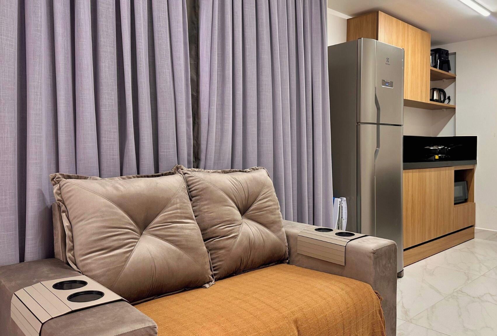 A modern living room with a sofa, a built-in coffee table, a refrigerator, and a microwave.