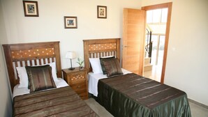A hotel room with two beds, wooden headboards, a nightstand with a lamp, and framed pictures on the wall. - 4 Bedroom Villa Sleeps 8 With Private Pool (Vera)