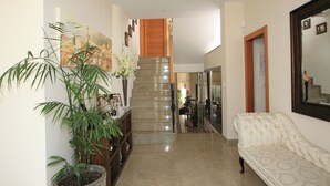 A hallway with a staircase, a sofa, and a large mirror. - 4 Bedroom Villa Sleeps 8 With Private Pool (Vera)