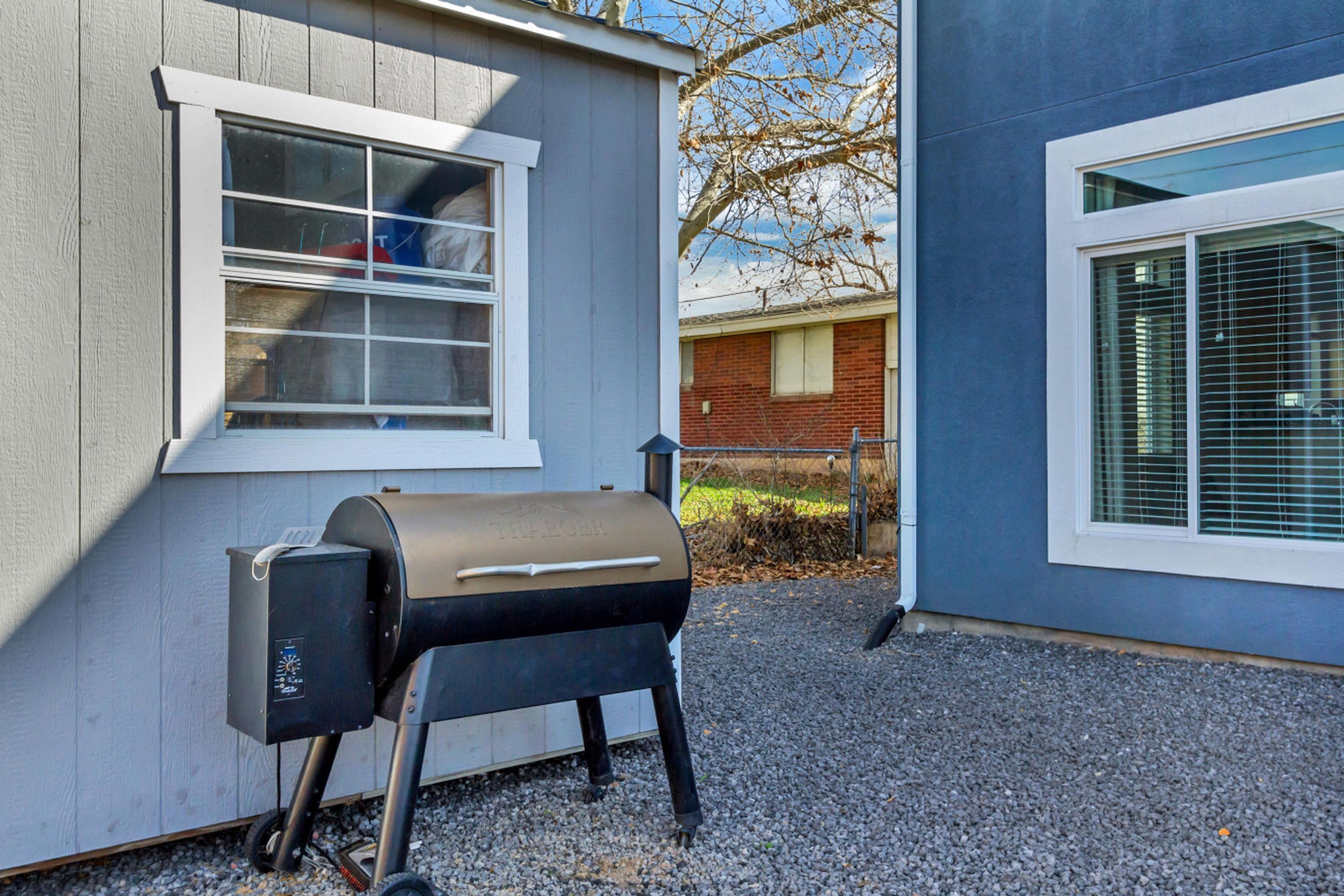 A portable grill outside a house with a window and a door.