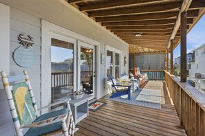 Eine überdachte Veranda mit Holzterrasse, weißen Wänden und einem blauen Stuhl.