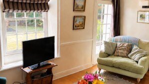 Un soggiorno con televisione, divano, tavolino da caffè e opere d'arte alle pareti.