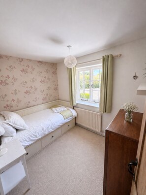 A bedroom with a single bed, a dresser, a radiator, and a window with curtains. - Country House near Deal & Sandwich (Tilmanstone)